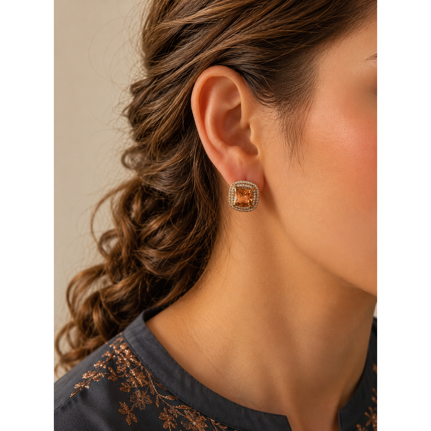 Woman wearing gold-tone cushion stud earrings with zircon halo in champagne  stone variant