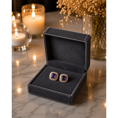 Gold-tone cushion-cut zircon stud earrings in royal purple shade displayed in charcoal graphite velvet jewelry box