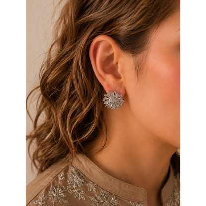 Woman wearing silver starburst zircon stud earrings with baguette crystal detailing and mocha embroidered outfit