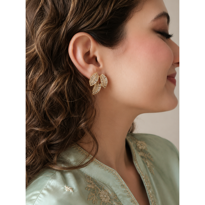 Woman wearing light gold crystal leaf cluster stud earrings with detailed leaf-inspired design and sparkling baguette stones.