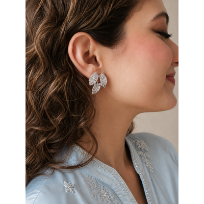 Woman wearing silver crystal leaf cluster stud earrings featuring sparkling baguette stones and botanical leaf design.