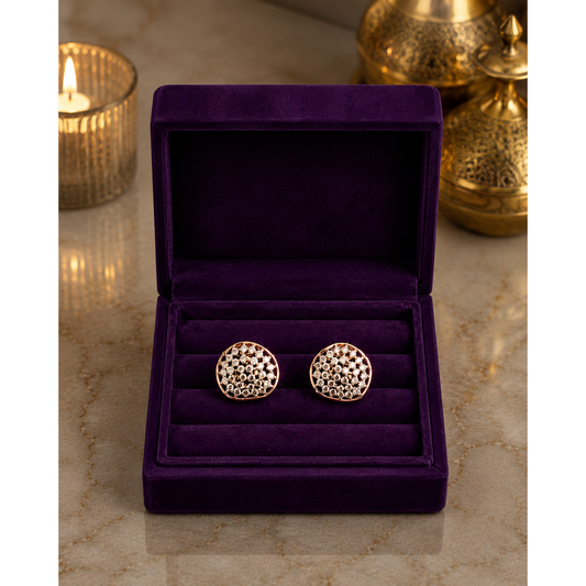 Artisan crystal cluster stud earrings in rose gold displayed inside a luxurious royal amethyst velvet jewelry box on a marble surface with warm candlelight ambiance.