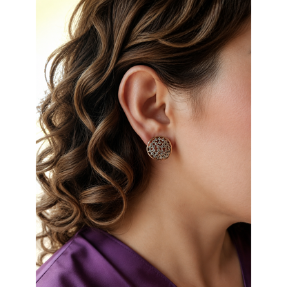Woman wearing artisan-inspired rose gold crystal cluster stud earrings with an organic wavy frame, styled with refined brown curls and a royal amethyst satin V-neck shirt.