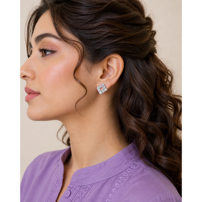 Silver square crystal stud earrings worn on ear with geometric open center design and polished finish