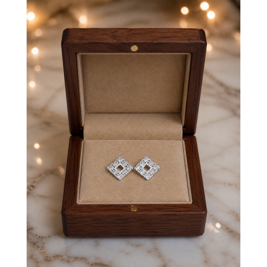 Silver square crystal stud earrings placed flat in wooden jewelry box with fawn velvet interior on marble surface