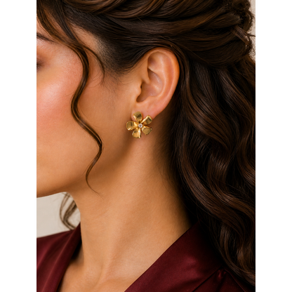 Gold floral stud earrings worn on ear with petal design and crystal center