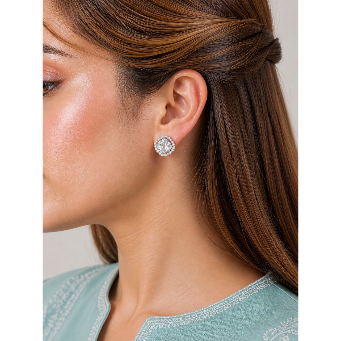 Silver square stud earrings with pearl border worn on ear with faceted center stone