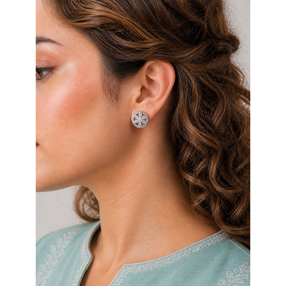 Close-up of a woman wearing silver floral earrings with a neutral background