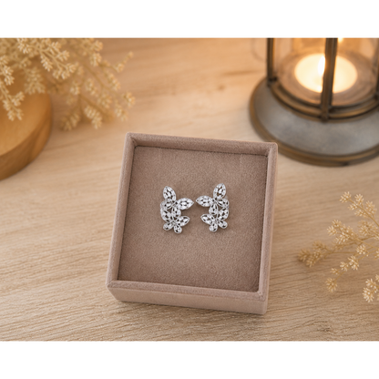 Crystal butterfly earrings displayed in light brown velvet jewelry box on wooden surface