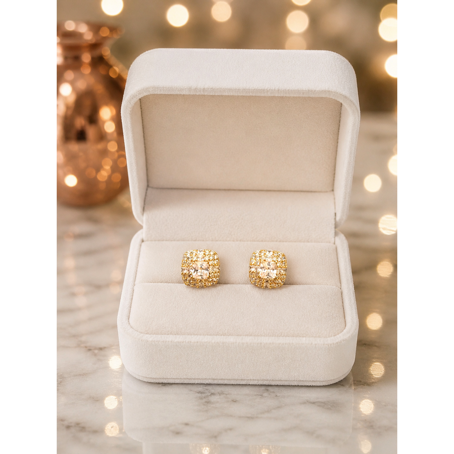 Gold crystal stud earrings displayed in ivory velvet jewelry box on marble surface with soft lighting