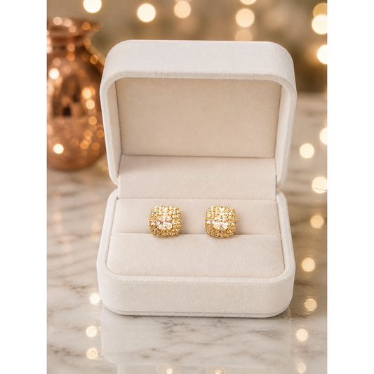 Gold crystal stud earrings displayed in ivory velvet jewelry box on marble surface with soft lighting