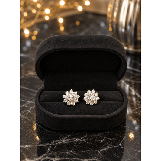 Silver flower stud earrings displayed in matte black oval velvet jewelry box on black marble with fairy lights background