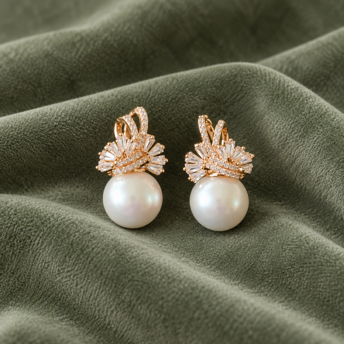 Pair of Gilded Fan Pearl Drop earrings in gold with clear baguette zircons and round pearl drops displayed on fabric.