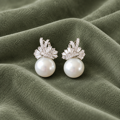 Pair of Gilded Fan Pearl Drop earrings in gold with clear baguette zircons and round pearl drops displayed on fabric.