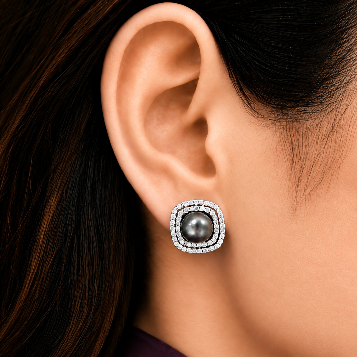 Close-up of Smoky Crest Stud worn on the ear, featuring a lustrous smoky grey pearl framed by two sparkling rows of clear zircon.
