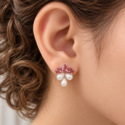 Close-up of Grape Dew Pearl Stud worn on the ear, showing three faceted ruby pink crystals and three pearl drops in a compact clustered silhouette.
