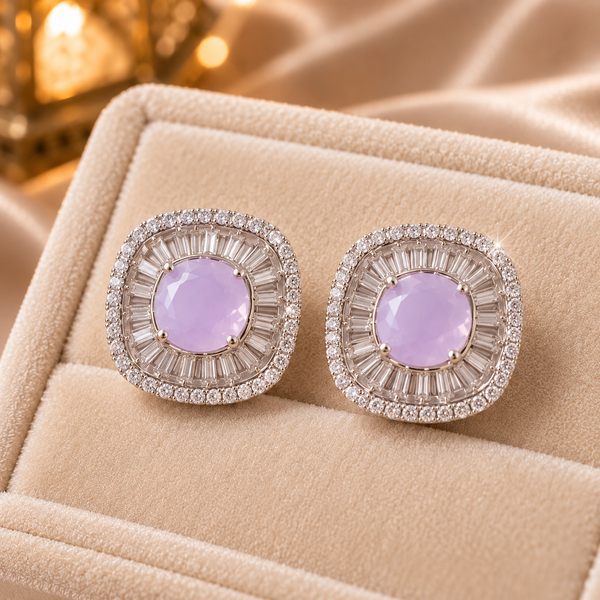Close-up of cushion-shaped stud earrings featuring a round pink centre stone surrounded by radiating baguette-cut and tiny clear zircons.