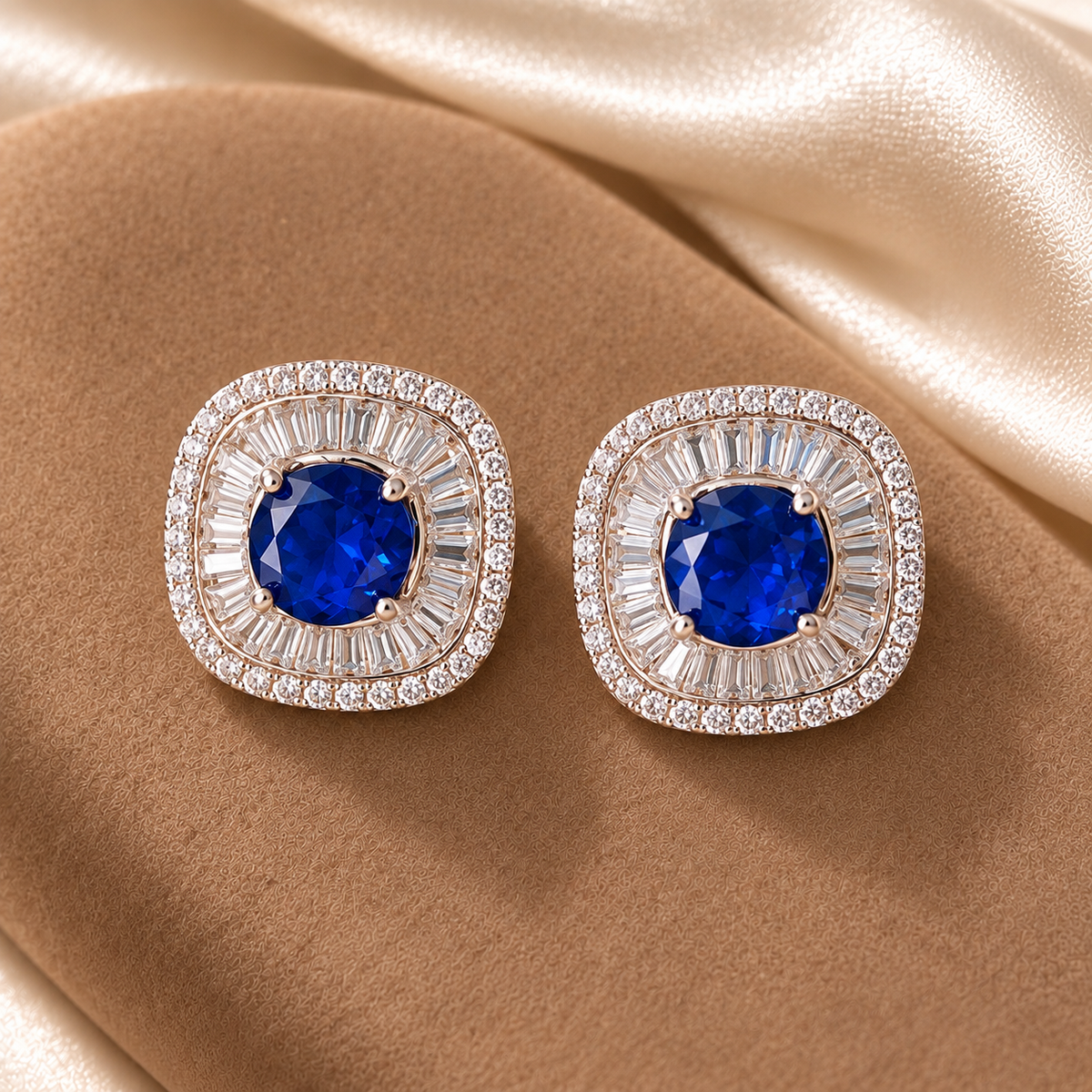 Close-up of cushion-shaped stud earrings featuring a round blue centre stone surrounded by radiating baguette-cut and tiny clear zircons.