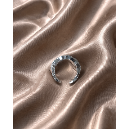 Silver textured open band ring placed on light brown satin fabric with soft folds