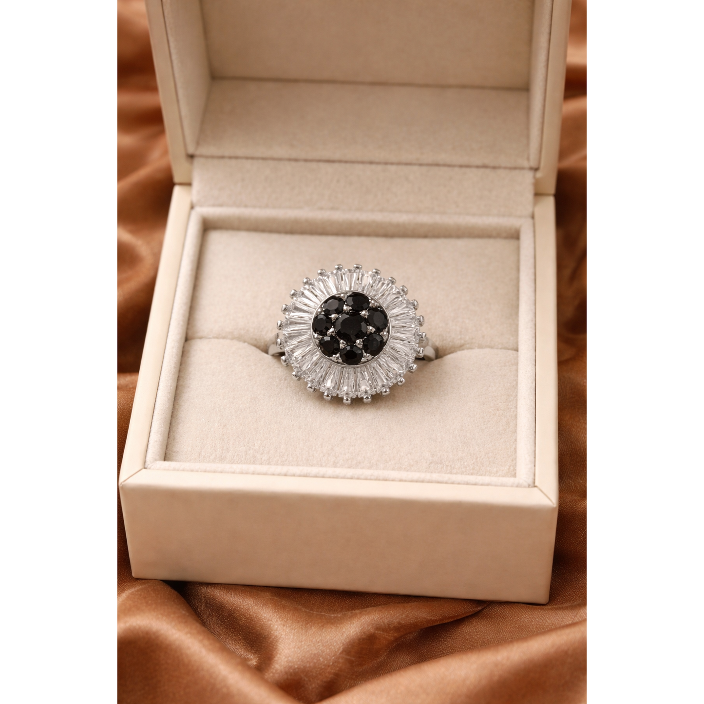 Gold halo statement ring with central black stones and baguette halo displayed in luxury jewelry box on satin fabric