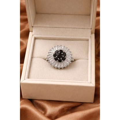 Gold halo statement ring with central black stones and baguette halo displayed in luxury jewelry box on satin fabric