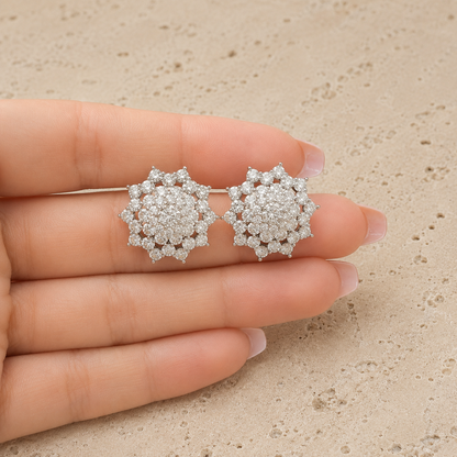 Pair of Astra Crest clear zircon cluster stud earrings displayed in a hand
