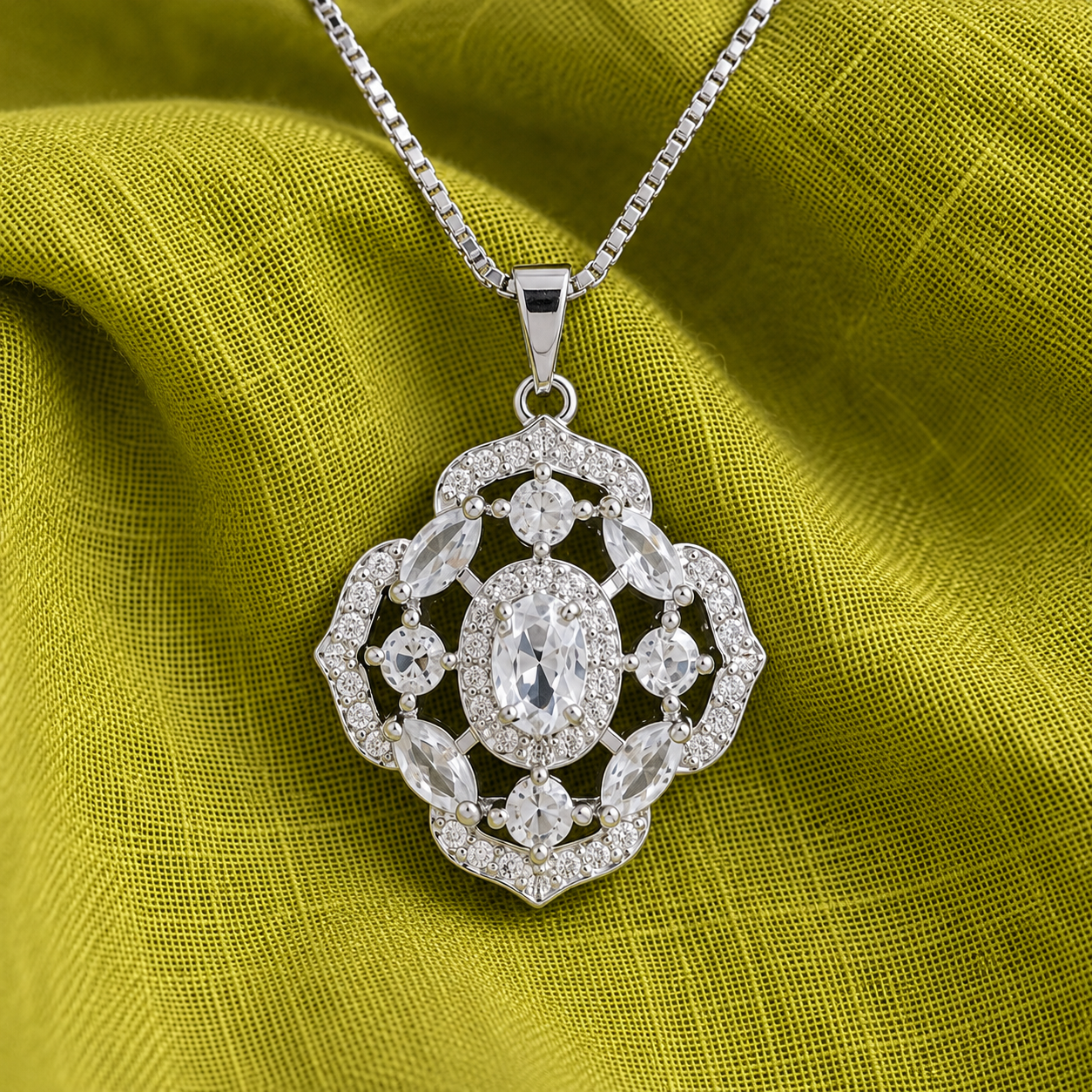 Close-up of intricate silver locket featuring a clear oval centre stone, marquise-cut clear accents and zircon-studded openwork detailing.