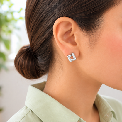 Woman wearing silver pavé geometric link stud earrings in a side-profile portrait