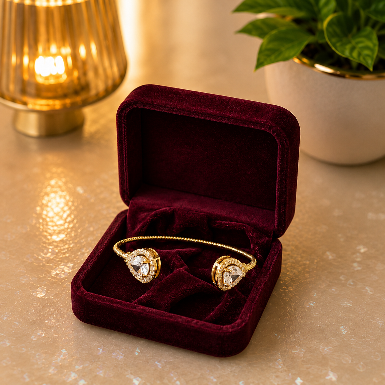 Gold open cuff bracelet with pear-cut crystal ends displayed inside a royal burgundy velvet bracelet case.
