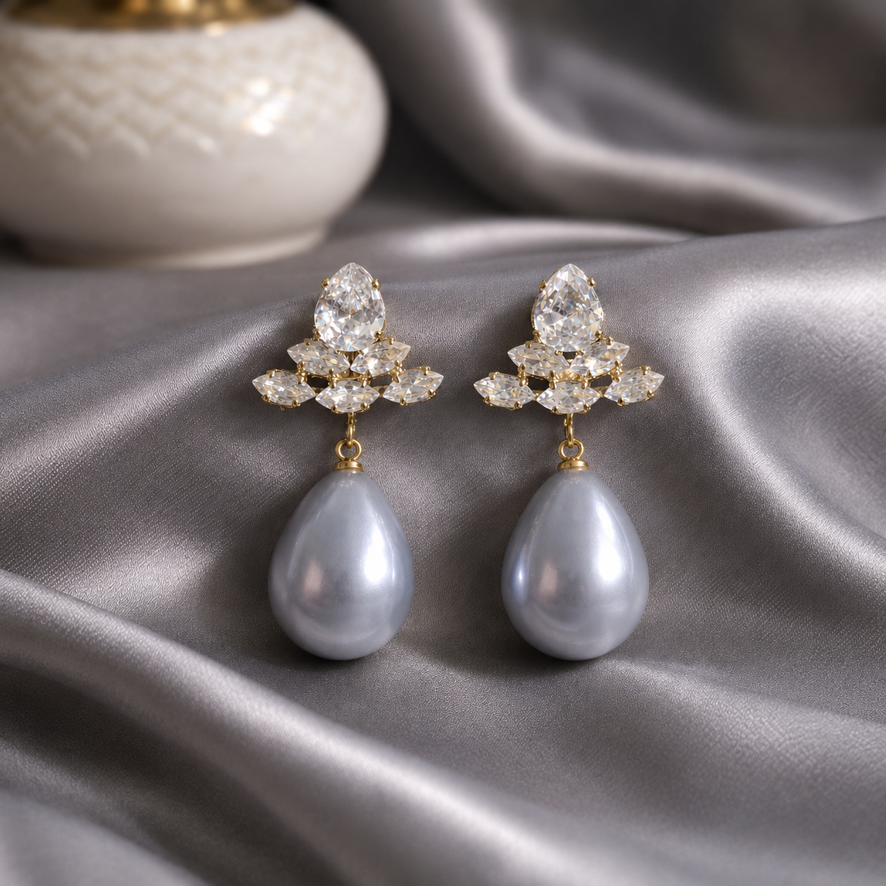 Gray pearl  teardrop crystal earrings displayed on grey satin with gold-tone crystal cluster