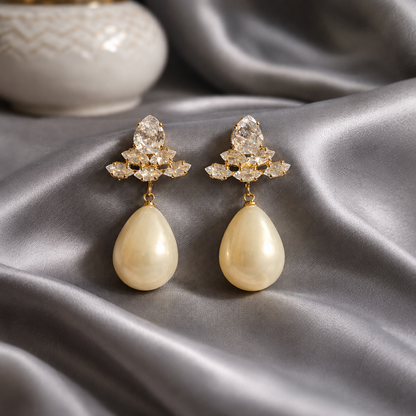 Pearl white teardrop crystal earrings displayed on grey satin with gold-tone crystal cluster