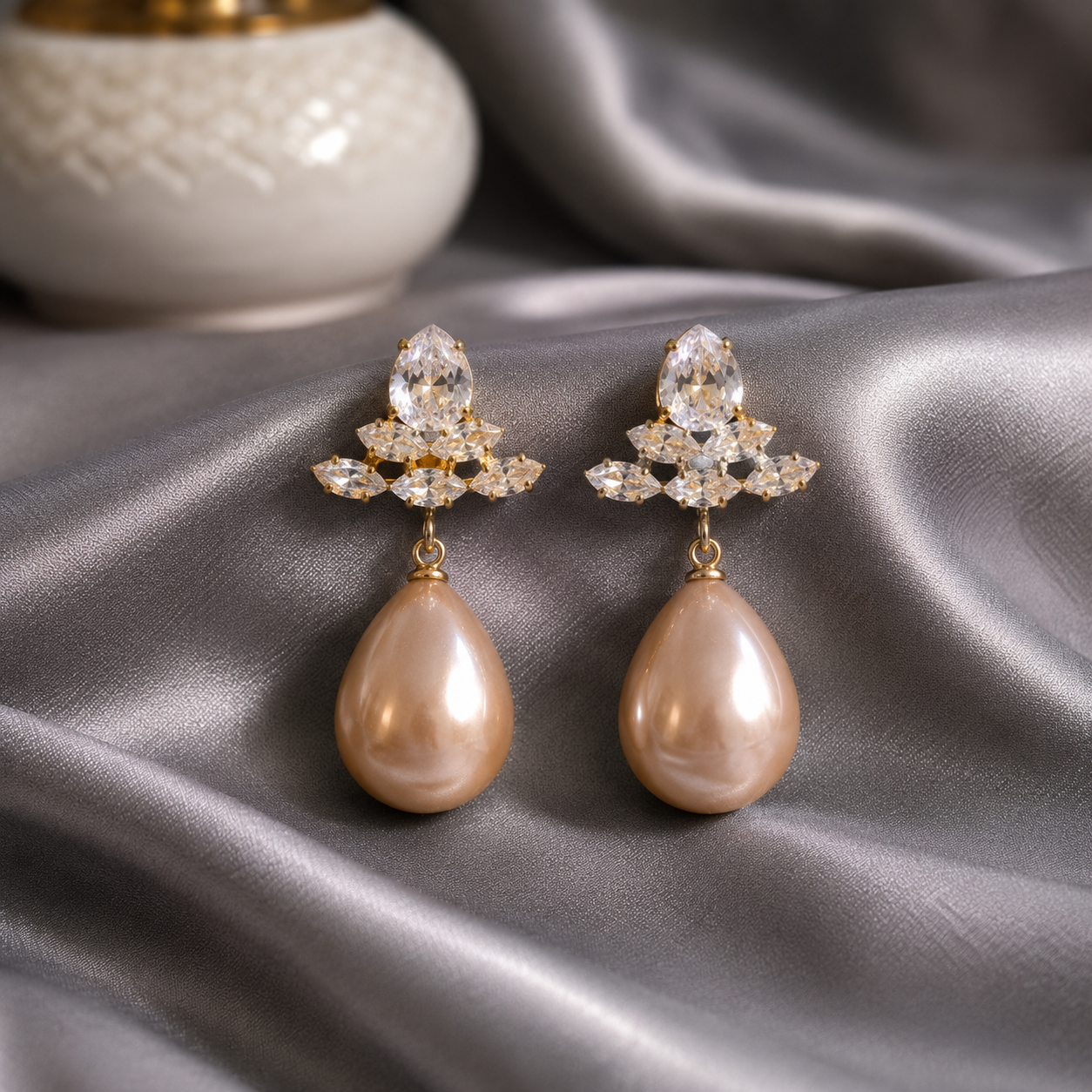 beige pearl teardrop crystal earrings displayed on grey satin with gold-tone crystal cluster