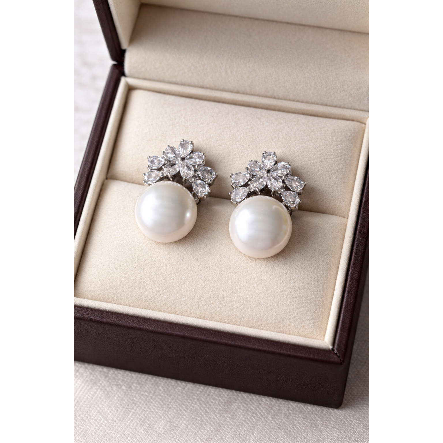 High-definition product photo of floral crystal and white pearl earrings displayed inside a premium velvet jewelry box
