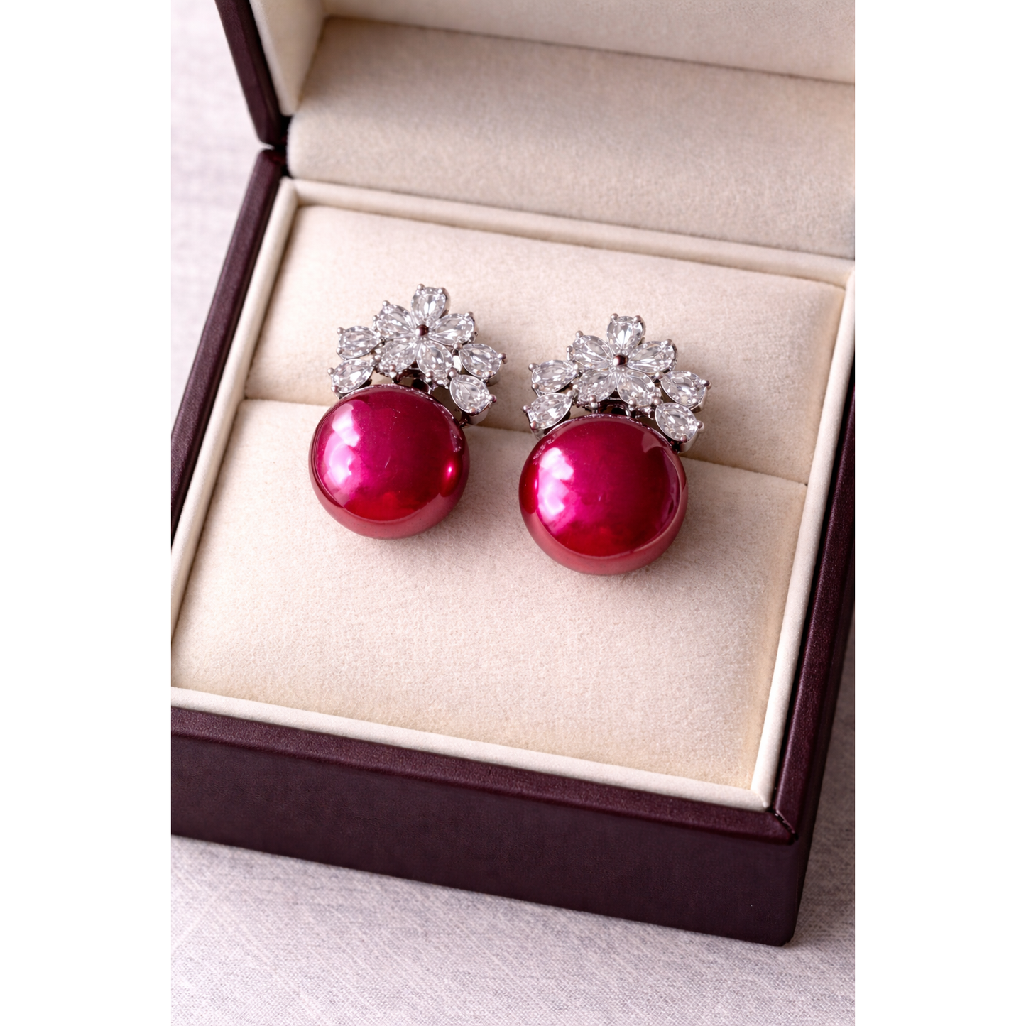 High-definition product photo of floral crystal and maroon pearl earrings displayed inside a premium velvet jewelry box