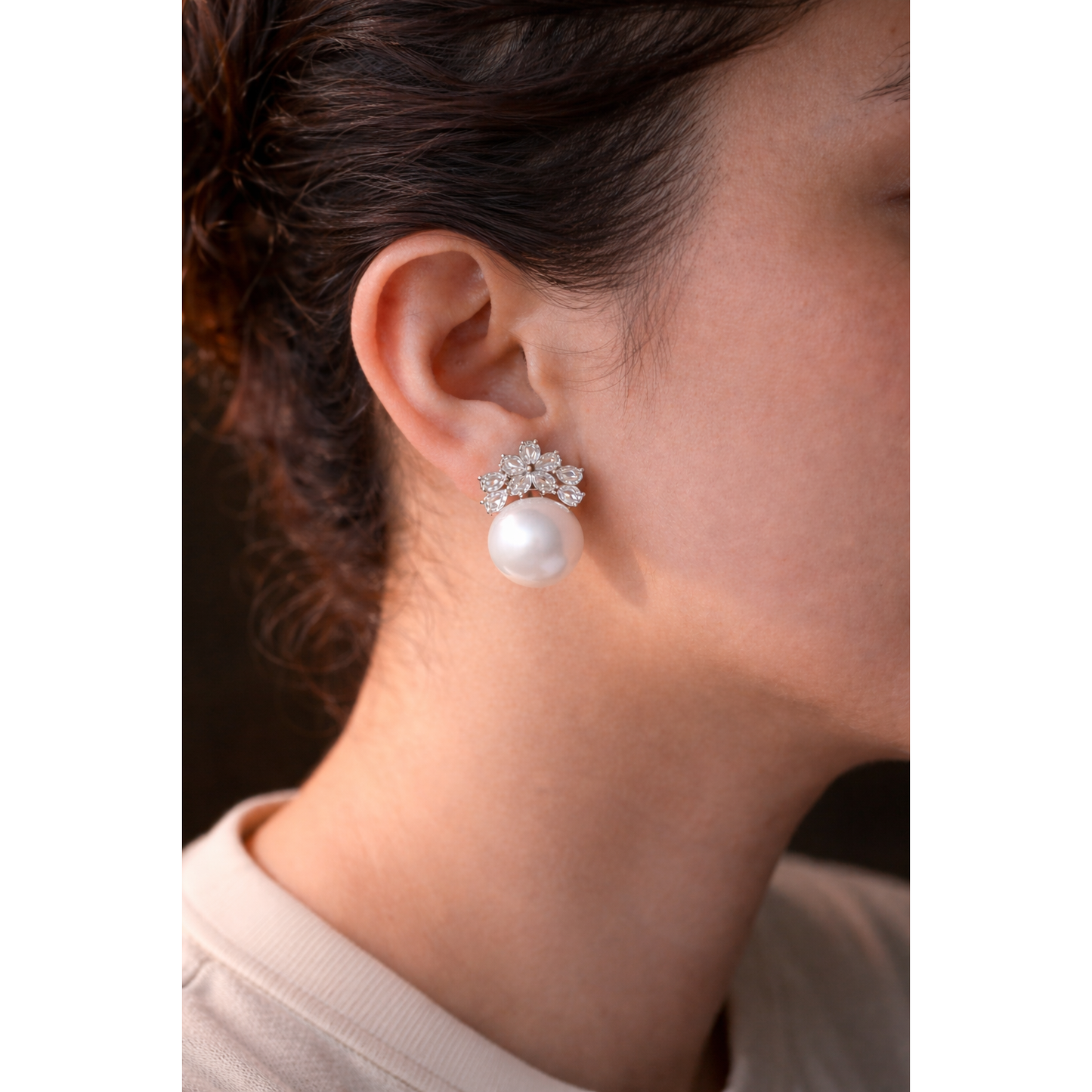 Close-up of a model wearing elegant floral crystal and pearl earrings