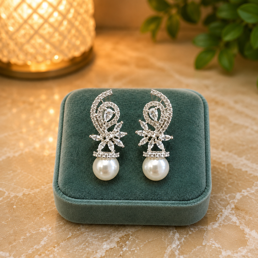Pearl drop crystal swirl earrings displayed on a premium sea green velvet cushion placed on a beige onyx stone with warm ambient lighting.