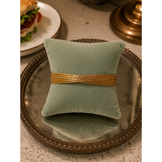 Elegant gold multi-strand twist cuff bracelet over a sage green sued bracelet cushion