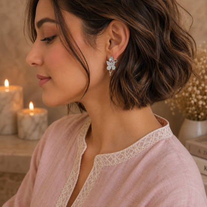 Woman wearing silver butterfly crystal earrings with a blush pink linen shirt in a side-profile luxury portrait.