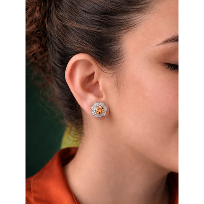 Close-up of a woman wearing a round earring with a central  champagne gemstone.