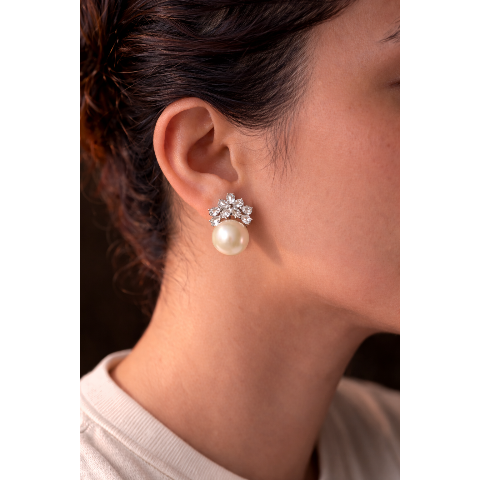 Close-up of a model wearing elegant floral crystal and ivory pearl earrings