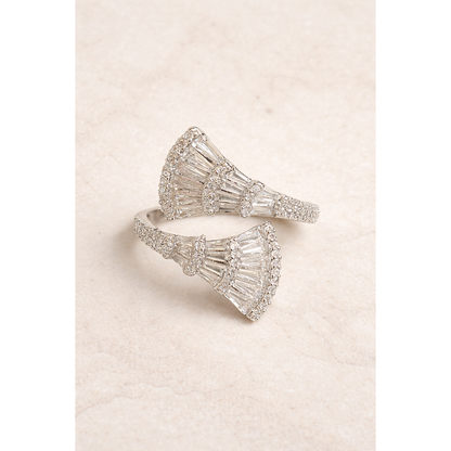 Silver fan-shaped baguette open wrap statement ring placed flat on light beige marble surface with soft studio lighting