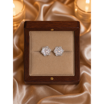 Silver floral crystal stud earrings placed flat in wooden jewelry box with light brown velvet on satin background