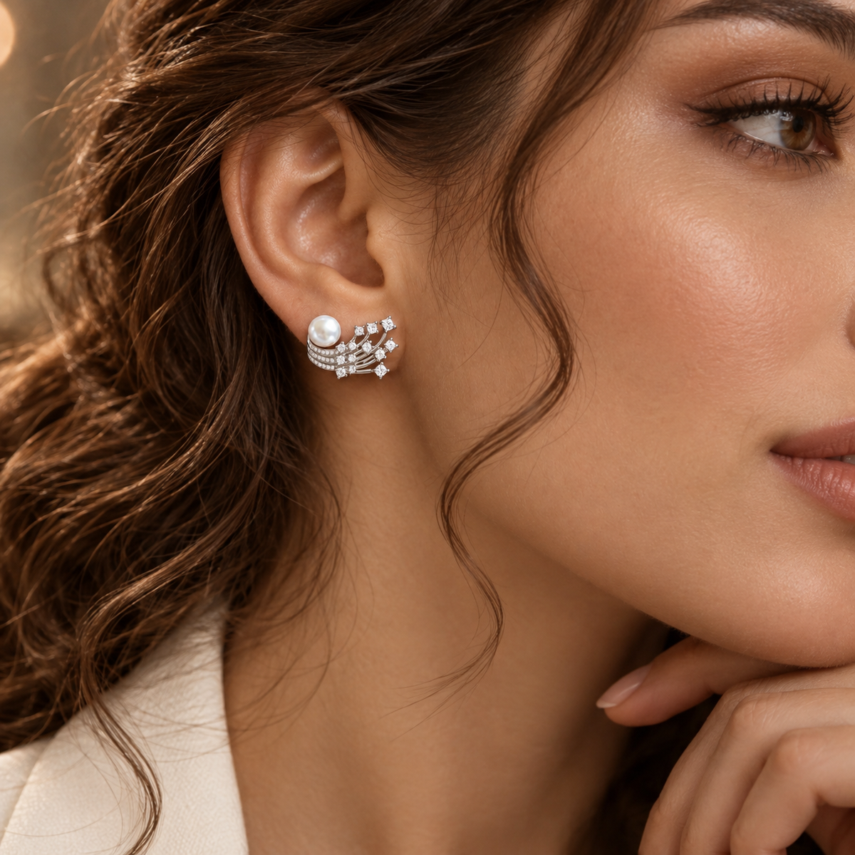 Close-up of a silver pearl and clear zircon statement earring sweeping across the earlobe.