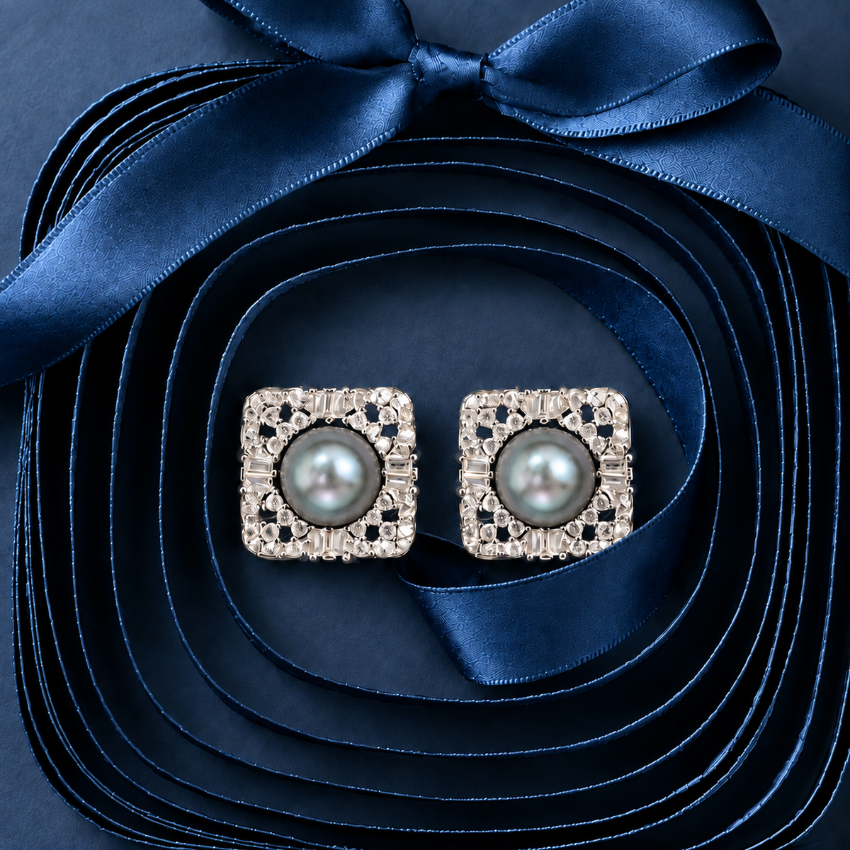 Close-up view of square pearl stud earrings highlighting the central pearl, openwork silver lattice and mixed zircon detailing.