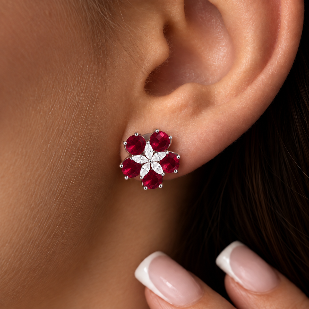 Close-up of Fivefold Bloom Stud worn on the ear, featuring five ruby red faceted stones surrounding a delicate five-petal clear crystal centre in silver-tone metal.