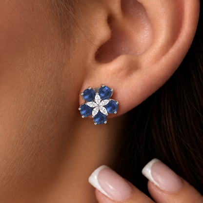 Close-up of Fivefold Bloom Stud worn on the ear, featuring five sapphire blue faceted stones surrounding a delicate five-petal clear crystal centre in silver-tone metal.