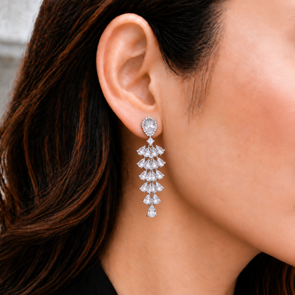 Close-up of S925 Cascade Prism Drop Earring worn on the ear, showing cascading pear-cut clear zircon stones in a long tapered silver design.