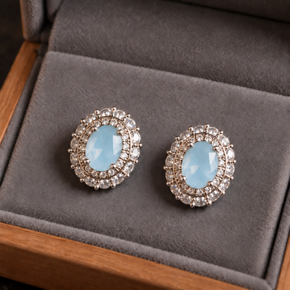 Close-up of silver S925 stud earrings featuring faceted oval  sea blue centre stones with intricate clear zircon 