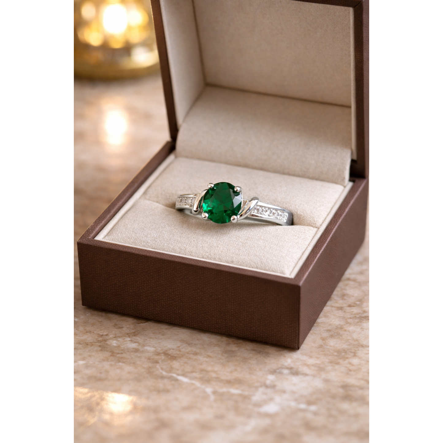 Round cut gemstone twist solitaire ring in silver emerald  green gemstone finish displayed inside beige luxury jewelry box
