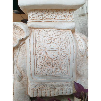 A close-up of a carved wooden pedestal with three elephant figures serving as legs, showcasing intricate details on their bodies and heads